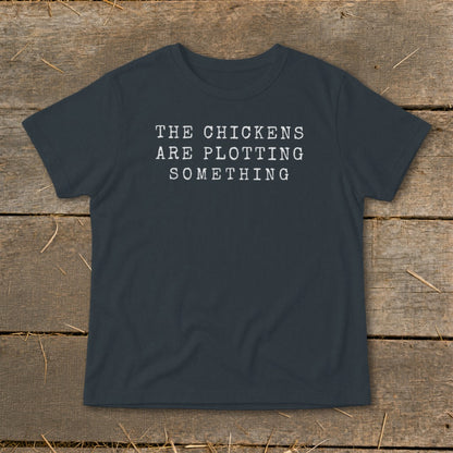 Dark gray t-shirt with white text reading "THE CHICKENS ARE PLOTTING SOMETHING".