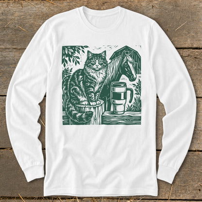 Green linocut graphic of a cat, horse, mug, and barn on a white long-sleeve shirt.