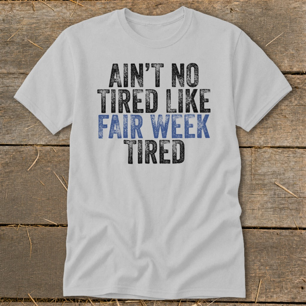 White t-shirt with distressed text reading "Ain't No Tired Like Fair Week Tired".