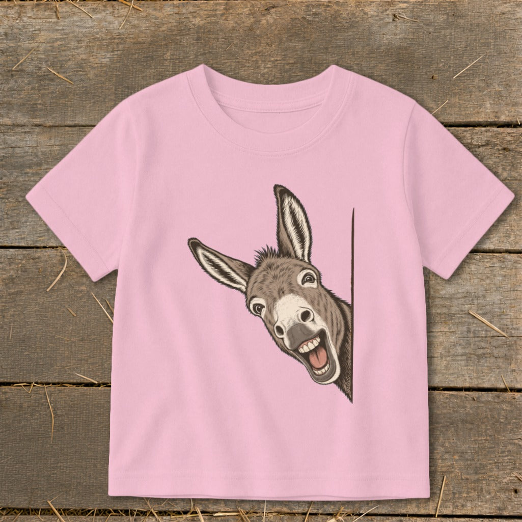 Pink t-shirt with a cartoon donkey peeking around a corner with a wide grin.