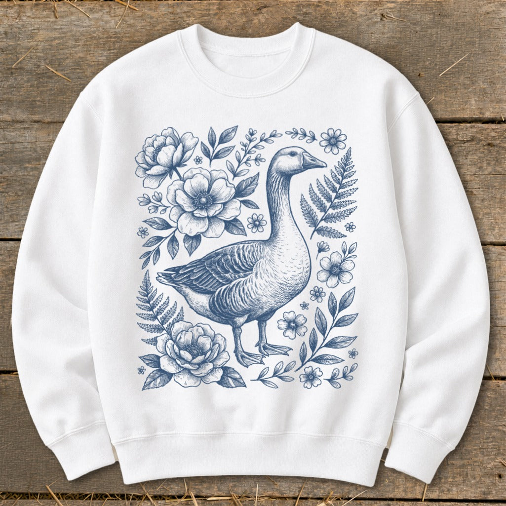 White crewneck sweatshirt with a blue line drawing of a goose surrounded by flowers and ferns.