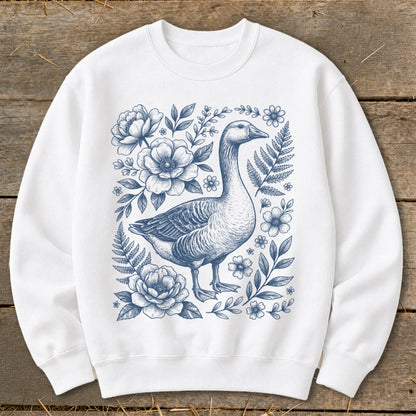 White crewneck sweatshirt with a blue line drawing of a goose surrounded by flowers and ferns.