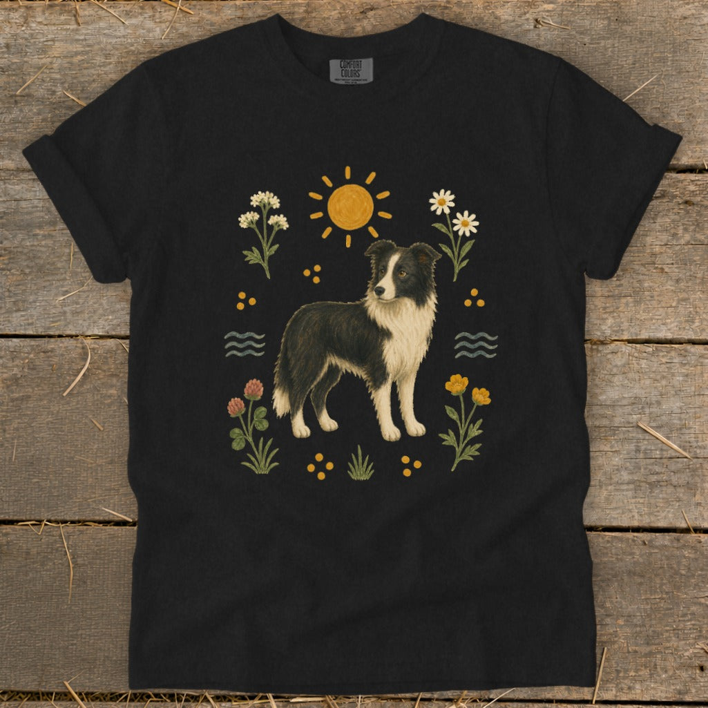 Black t-shirt with a painted Border Collie surrounded by flowers, sun, and water waves.