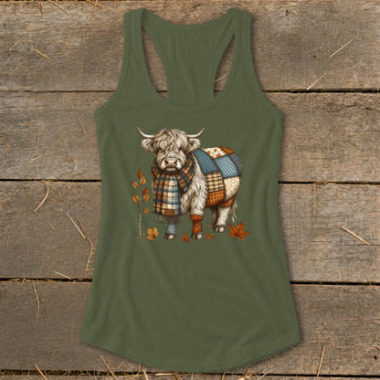 Highland cow with patchwork coat and scarf, surrounded by autumn leaves.