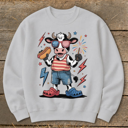 Cartoon cow wearing American flag sunglasses and holding a hot dog.