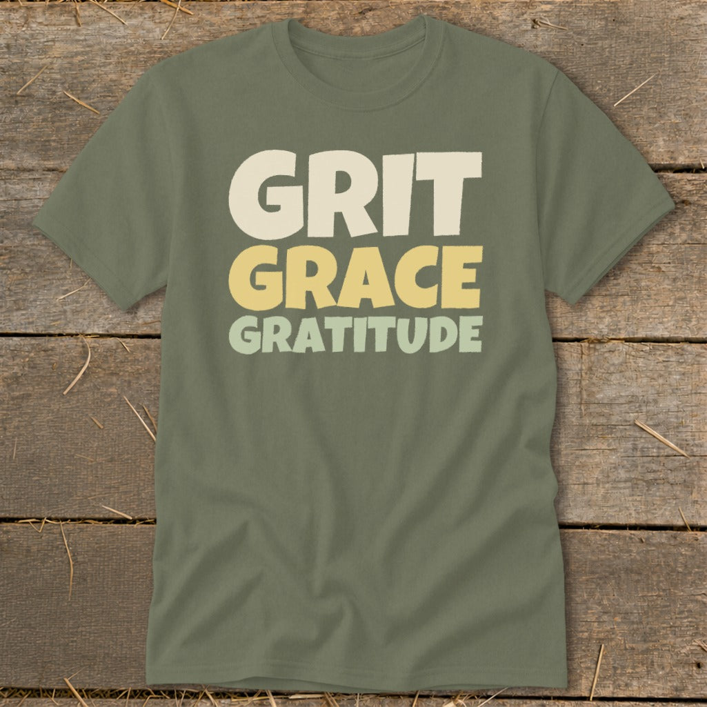 Olive green short-sleeved t-shirt featuring the stacked text "GRIT GRACE GRATITUDE" in cream, yellow, and sage.