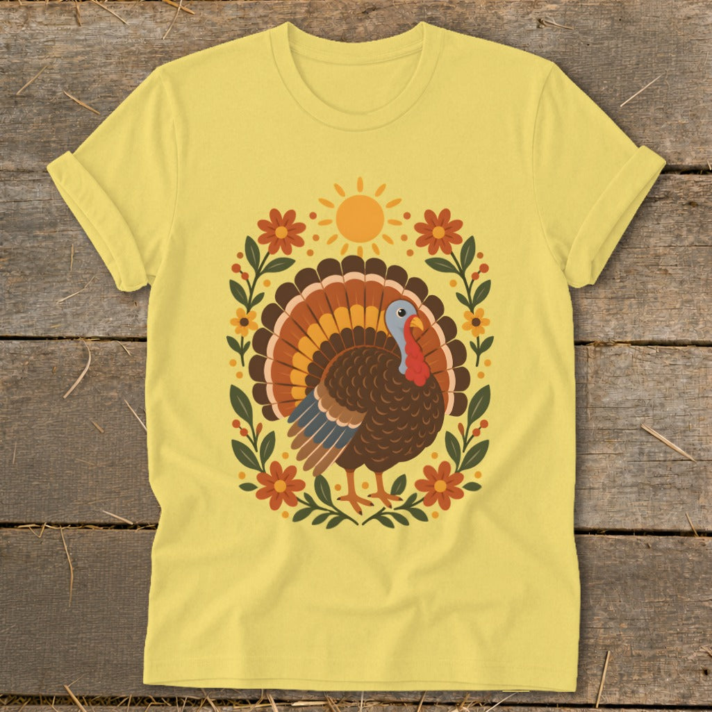 Yellow t-shirt featuring a decorative turkey illustration surrounded by flowers and a sun.