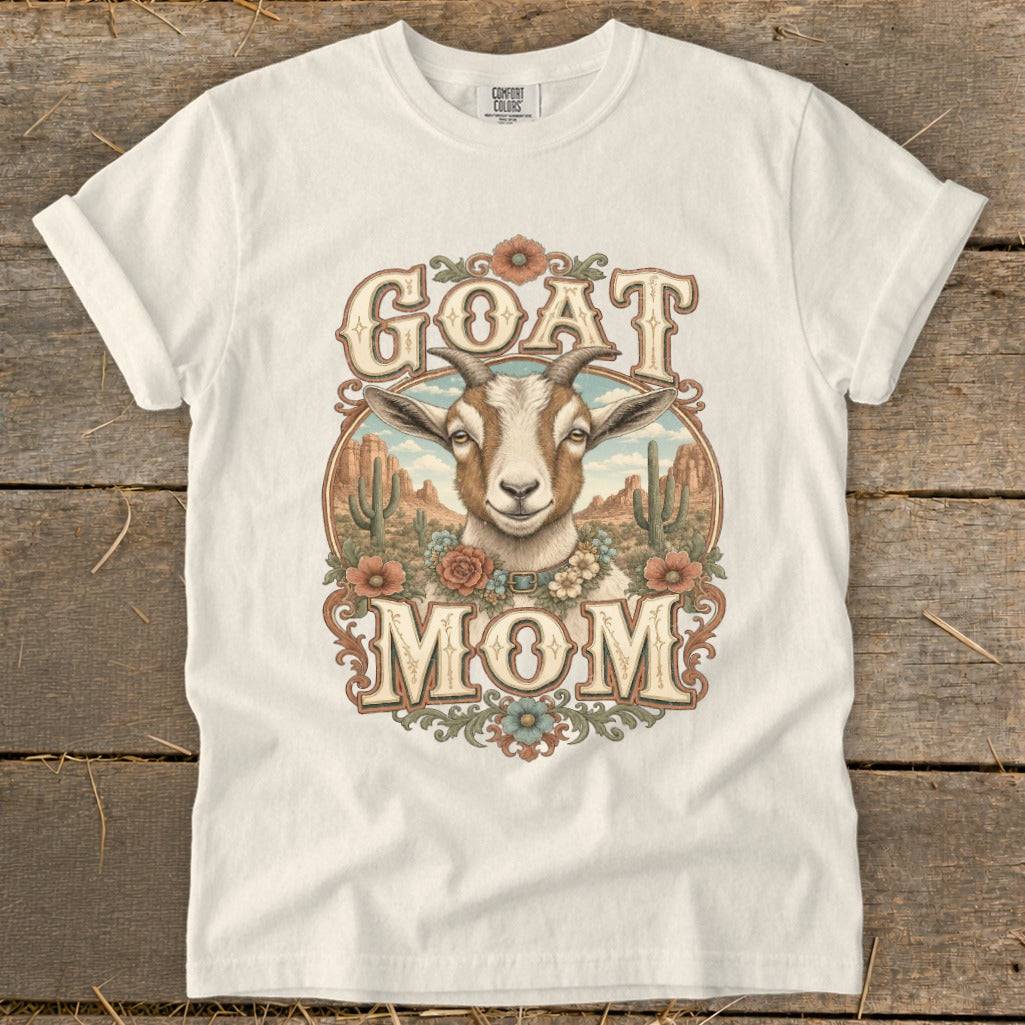White t-shirt with "GOAT MOM" text and a goat illustration in a desert landscape.