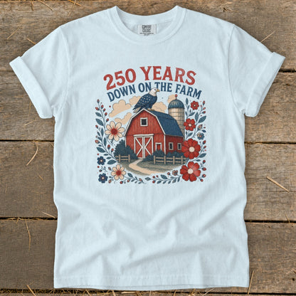 White t-shirt with red text "250 YEARS DOWN ON THE FARM", barn, eagle, and flowers.