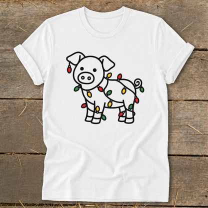 A white t-shirt featuring a cartoon pig wrapped in colorful Christmas lights, displayed on a wooden surface.