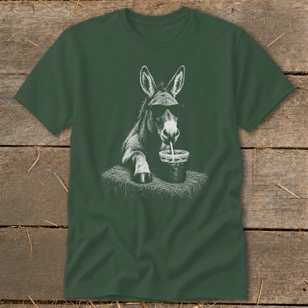 Donkey wearing sunglasses drinks from a cup with a straw on a bale of hay.