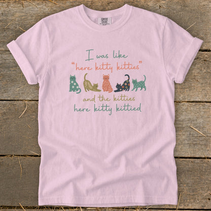 Pink t-shirt with "here kitty kitties and the kitties here kitty kittied" text and colorful cats.