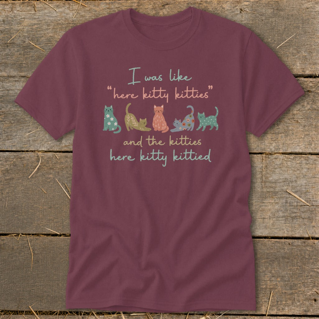 Burgundy t-shirt with cartoon cats and text: "I was like 'here kitty kitties' and the kitties here kitty kittied."
