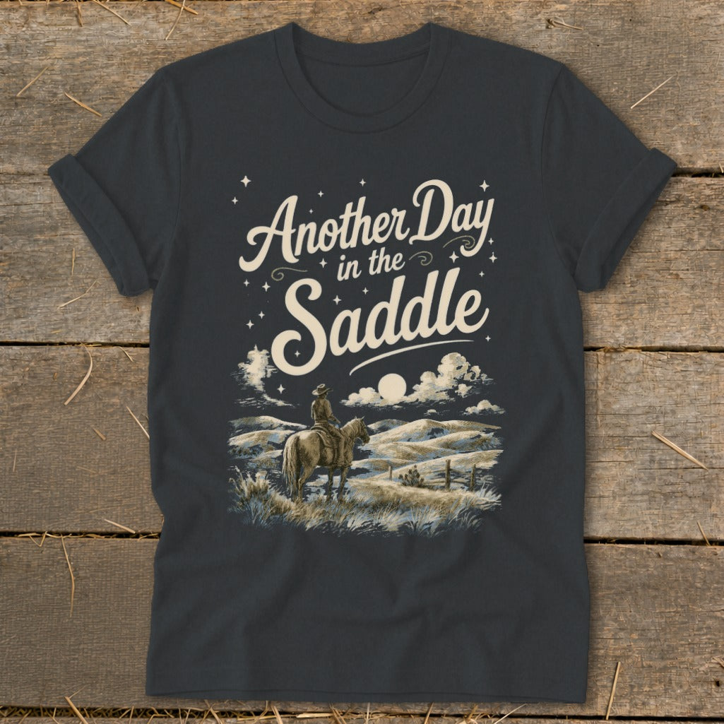T-shirt graphic with text "Another Day in the Saddle" and a cowboy on horseback.