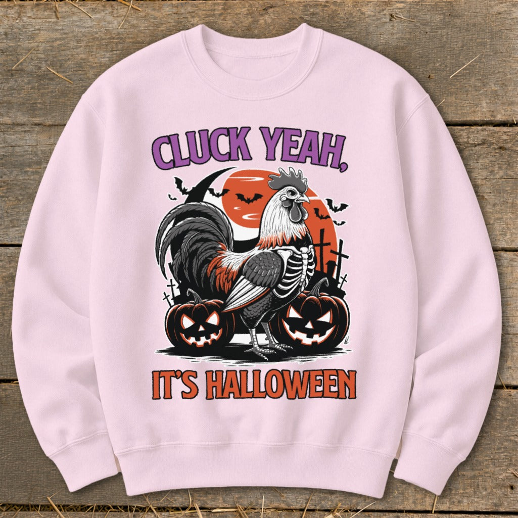 Pink sweatshirt with Halloween graphic featuring a skeleton rooster, pumpkins, and text "CLUCK YEAH, IT'S HALLOWEEN".