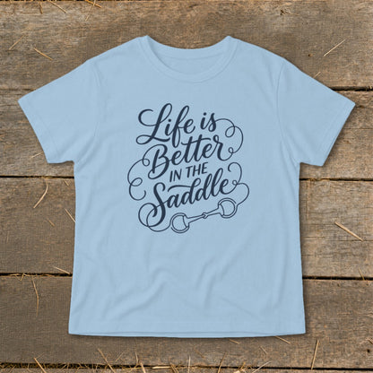 Light blue t-shirt with navy blue text reading "Life is Better In The Saddle" and a horse bit graphic.
