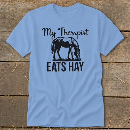 Light blue t-shirt with black text and horse graphic: "My Therapist Eats Hay".