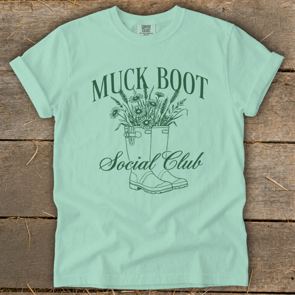 Mint t-shirt with green Muck Boot Social Club design featuring boots filled with flowers.