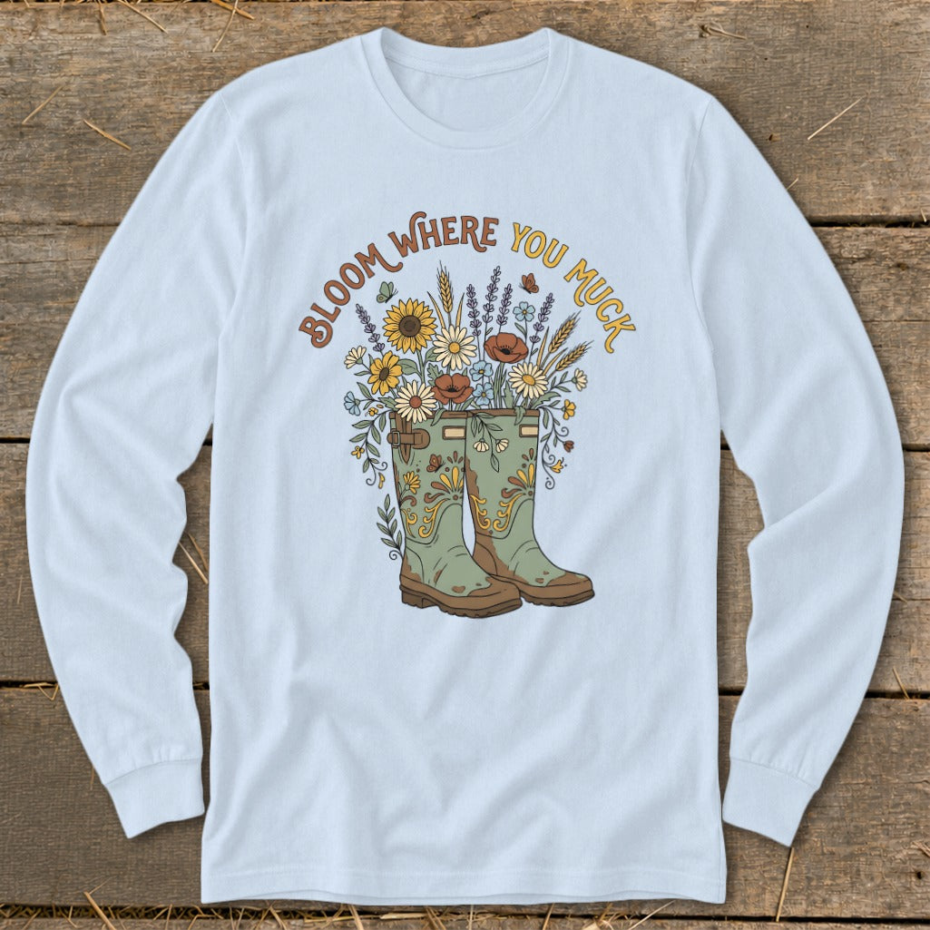 Light blue long-sleeve shirt with "Bloom Where You Muck" text and floral cowboy boots.