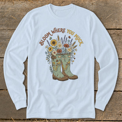 Light blue long-sleeve shirt with "Bloom Where You Muck" text and floral cowboy boots.