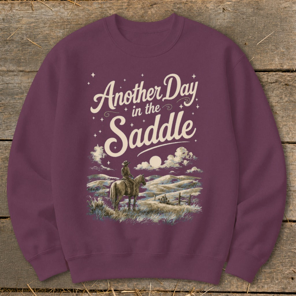 Maroon sweatshirt with "Another Day in the Saddle" text and cowboy on horseback.