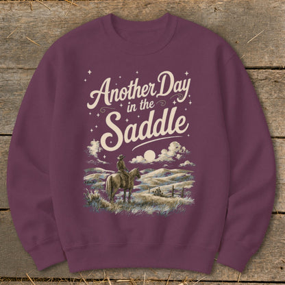 Maroon sweatshirt with "Another Day in the Saddle" text and cowboy on horseback.