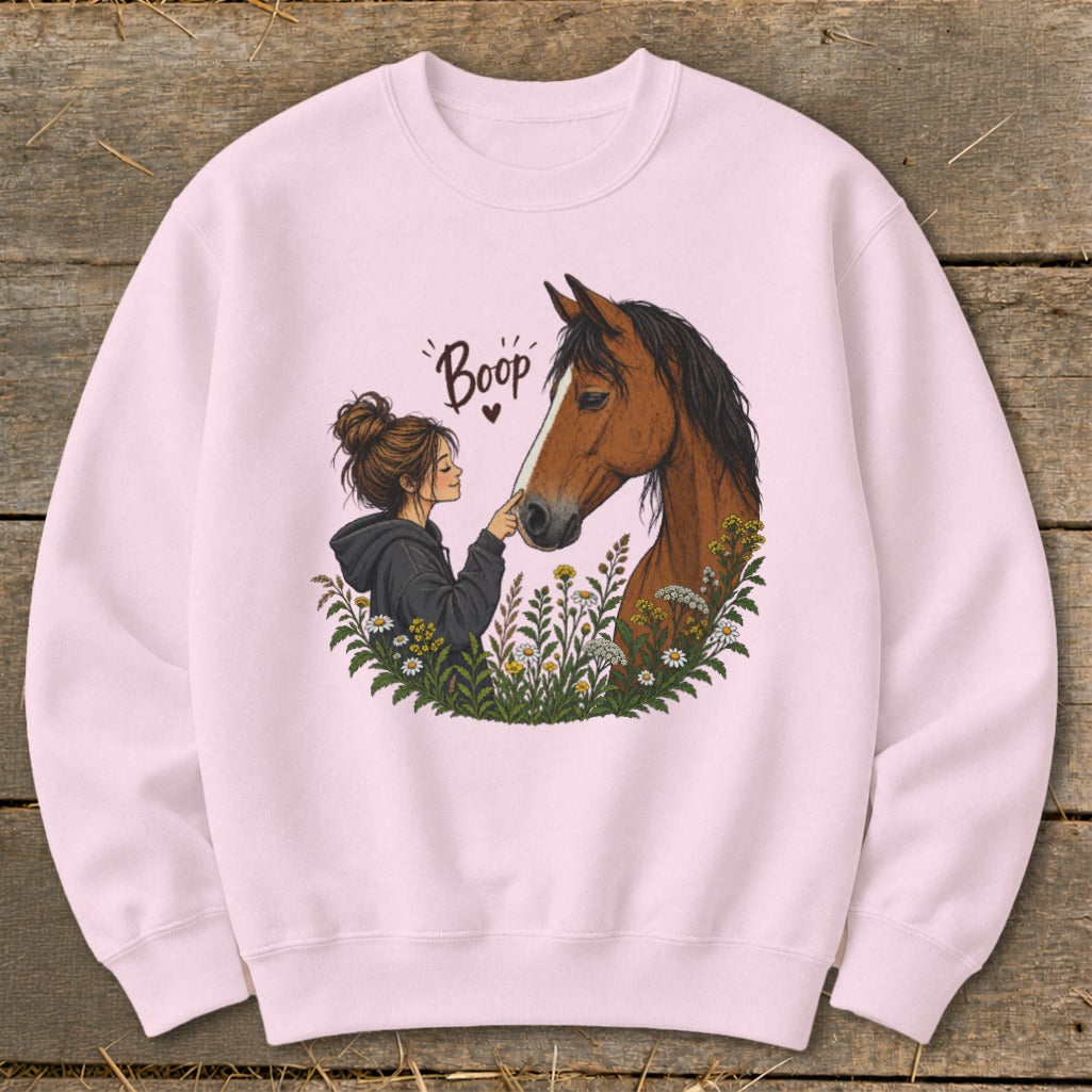 Pink sweatshirt with illustration of girl booping a horse's nose, surrounded by flowers.