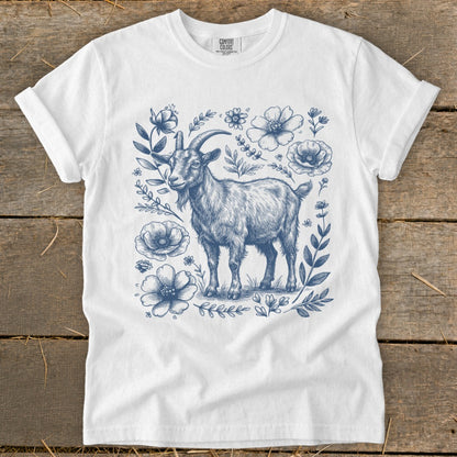 White t-shirt with blue sketch of a goat surrounded by flowers and leaves.
