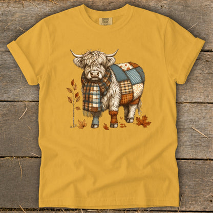 Yellow t-shirt with a patchwork Highland cow wearing a plaid scarf and autumn leaves.