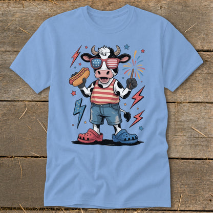 Cartoon cow in patriotic sunglasses holding hot dog and sparkler.