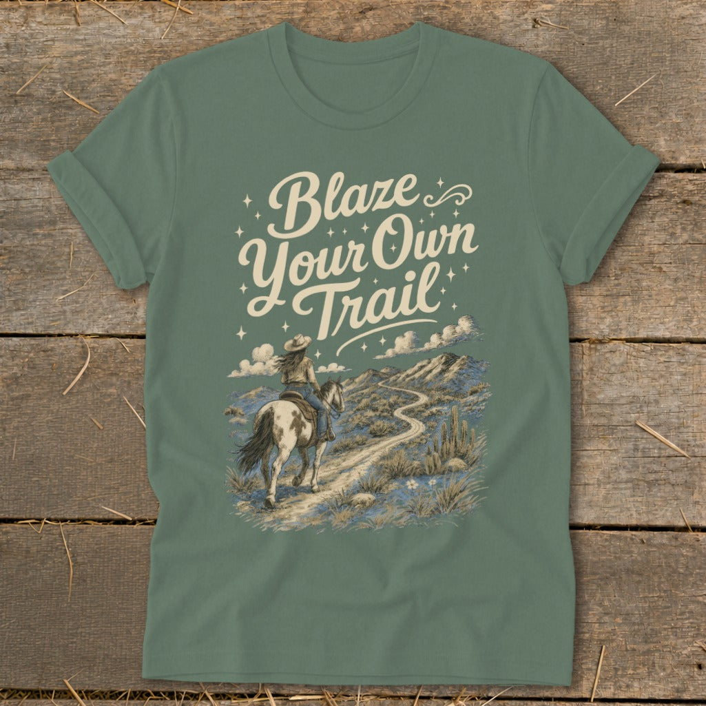 Green t-shirt with "Blaze Your Own Trail" text and a cowboy riding a horse on a desert path.