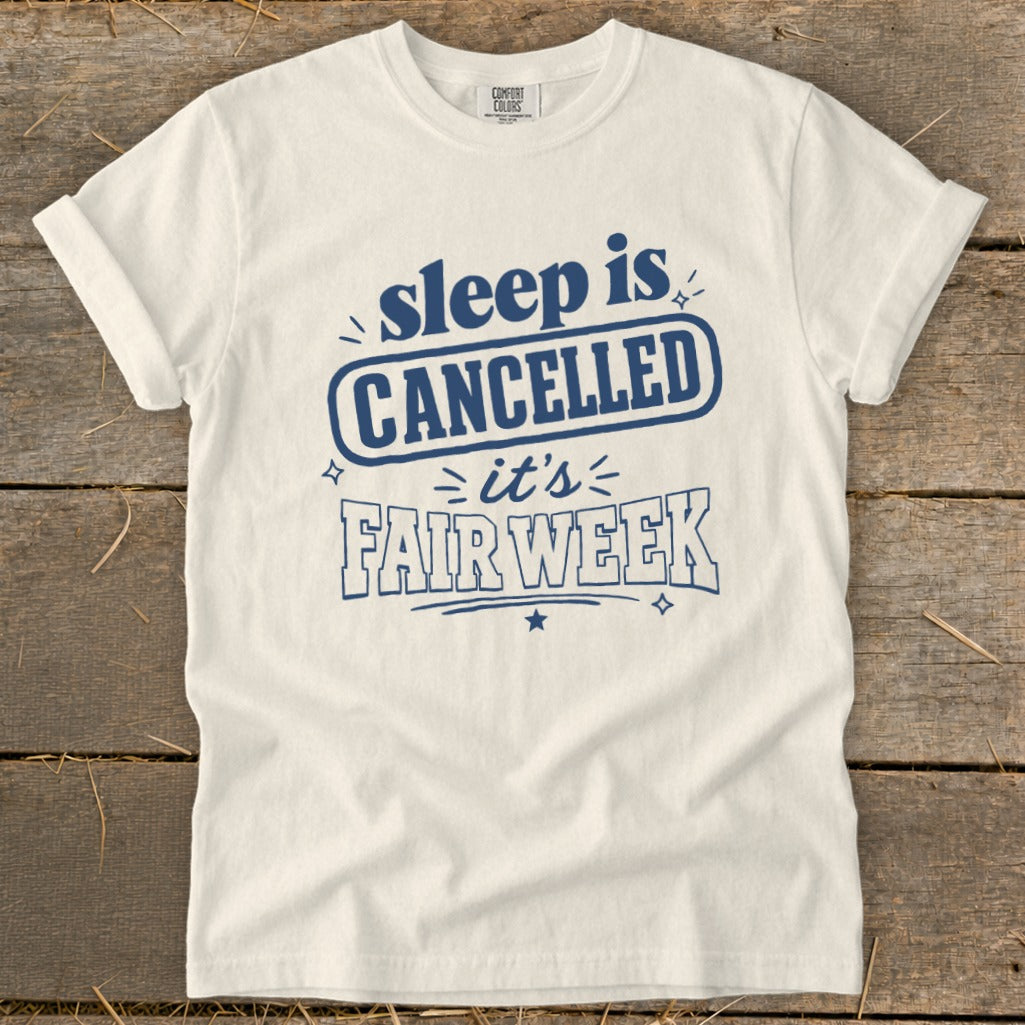 White t-shirt with dark blue text reading "sleep is CANCELLED it's FAIR WEEK".