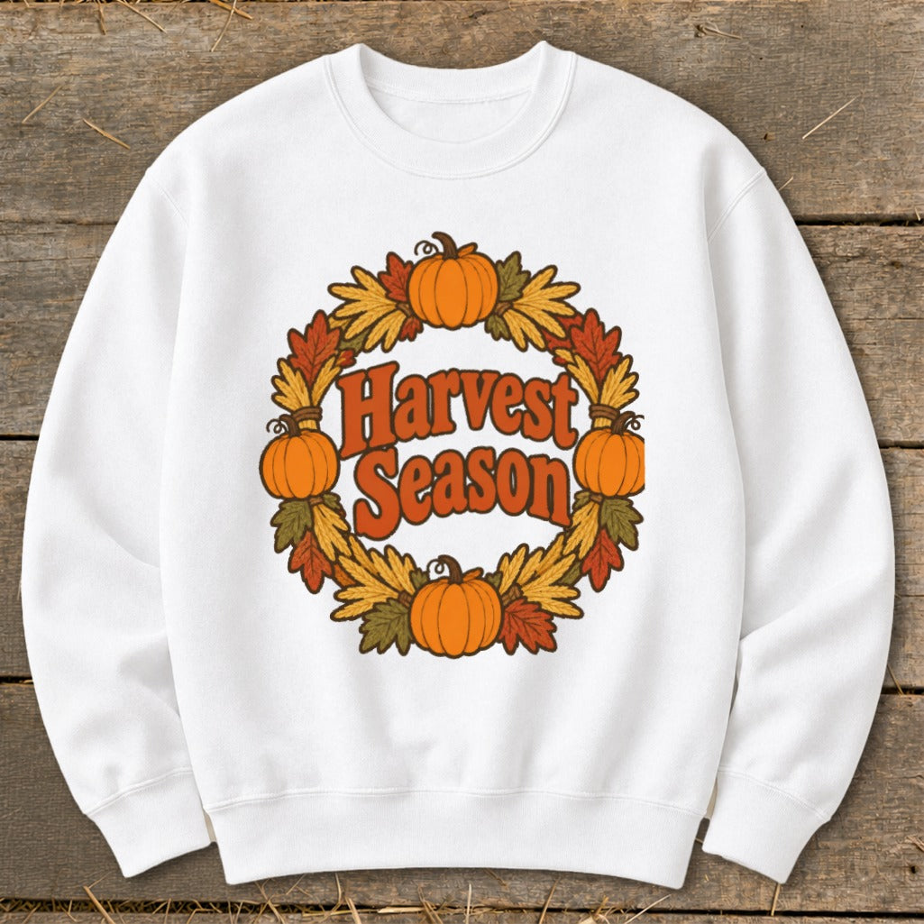 White sweatshirt with "Harvest Season" graphic in a wreath of pumpkins and fall leaves.