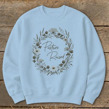 Light blue sweatshirt with "Pasture Raised" text inside a floral wreath.