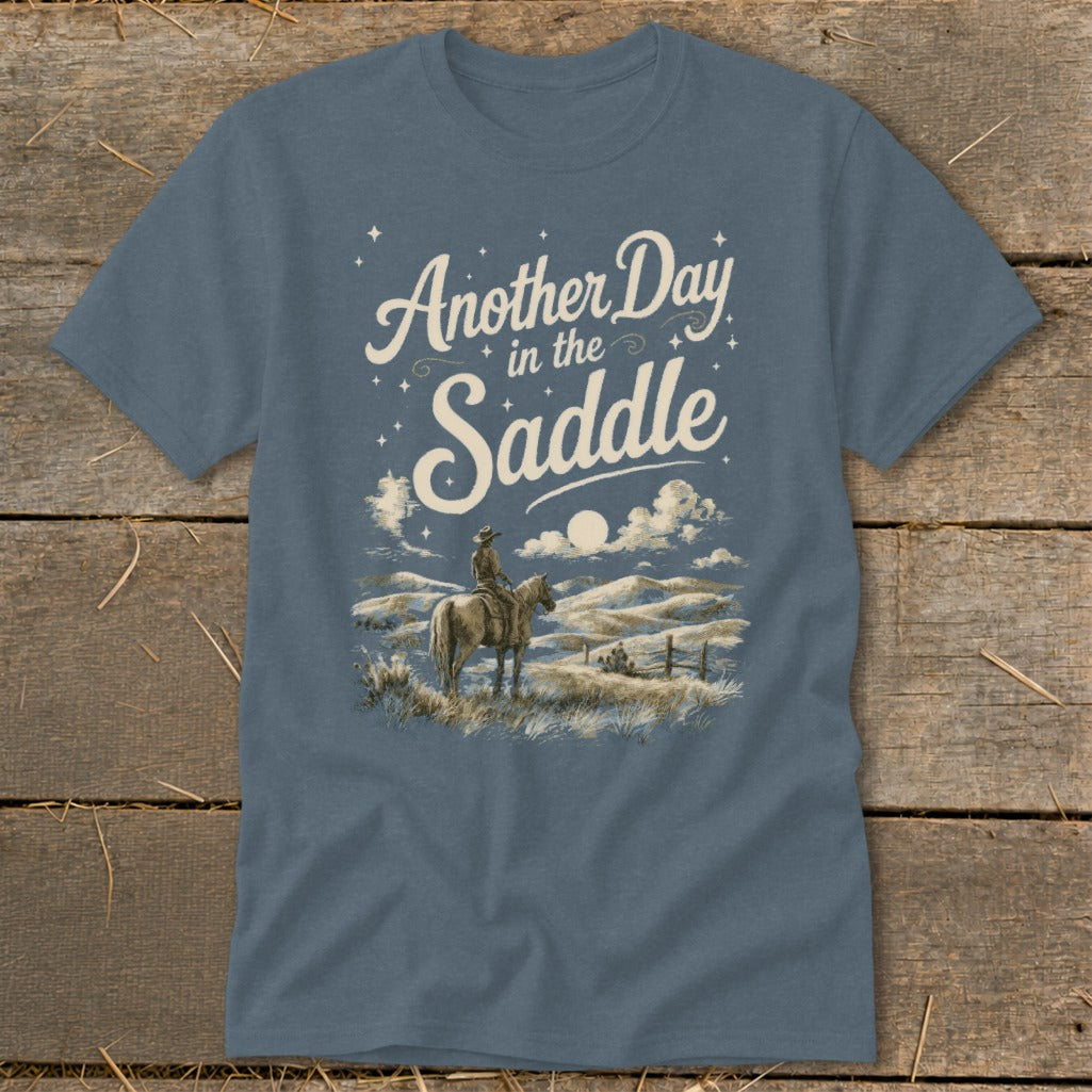 T-shirt with "Another Day in the Saddle" text and cowboy on horseback in landscape.