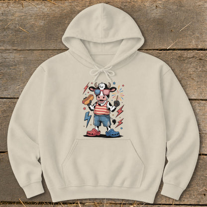 Cow wearing sunglasses and a striped shirt holds a hot dog and sparkler.