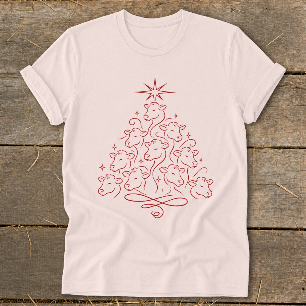 Red line art of cows forming a Christmas tree with a star on a pink t-shirt.