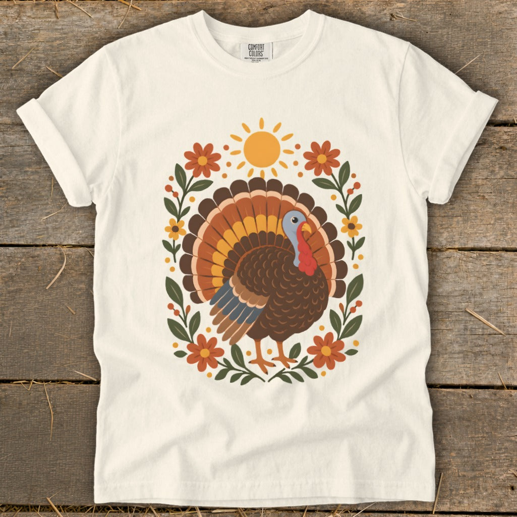 Cream t-shirt with a Thanksgiving turkey surrounded by flowers and sun graphic.