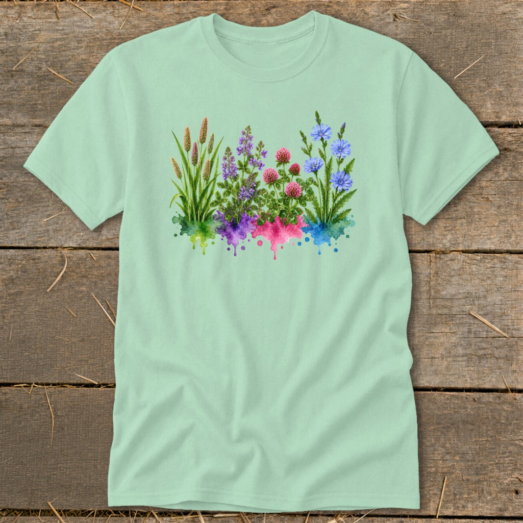 Light green crewneck t-shirt featuring a watercolor botanical graphic of wildflowers and grasses with colorful paint splatters.