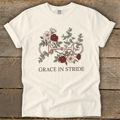 Cream t-shirt with horse bit floral graphic and "GRACE IN STRIDE" text.