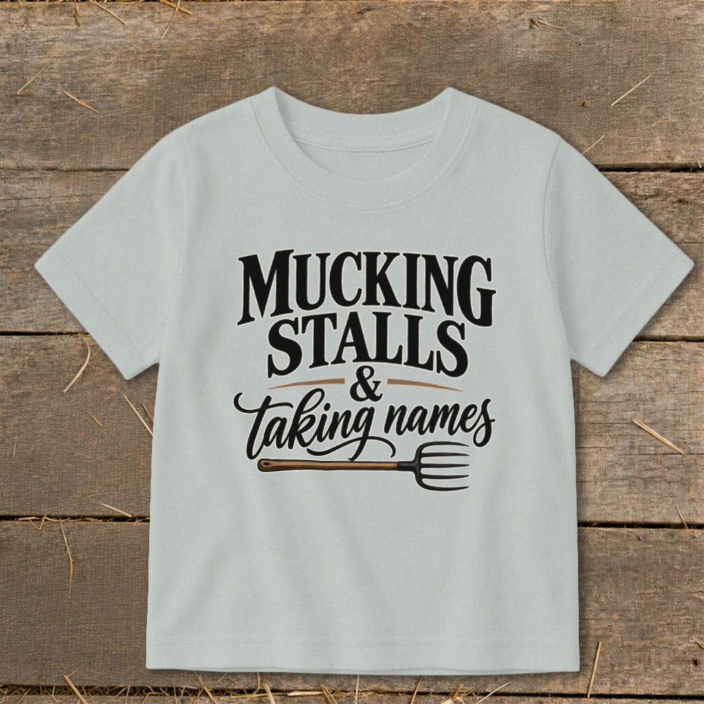 Light grey t-shirt with "MUCKING STALLS & taking names" text and pitchfork graphic.