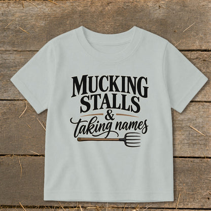 Light grey t-shirt with "MUCKING STALLS & taking names" text and pitchfork graphic.