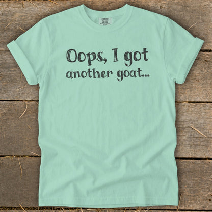 Mint t-shirt with black text reading "Oops, I got another goat...".