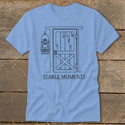 Light blue t-shirt with a line drawing of a barn door and lantern, and text "STABLE MOMENTS".
