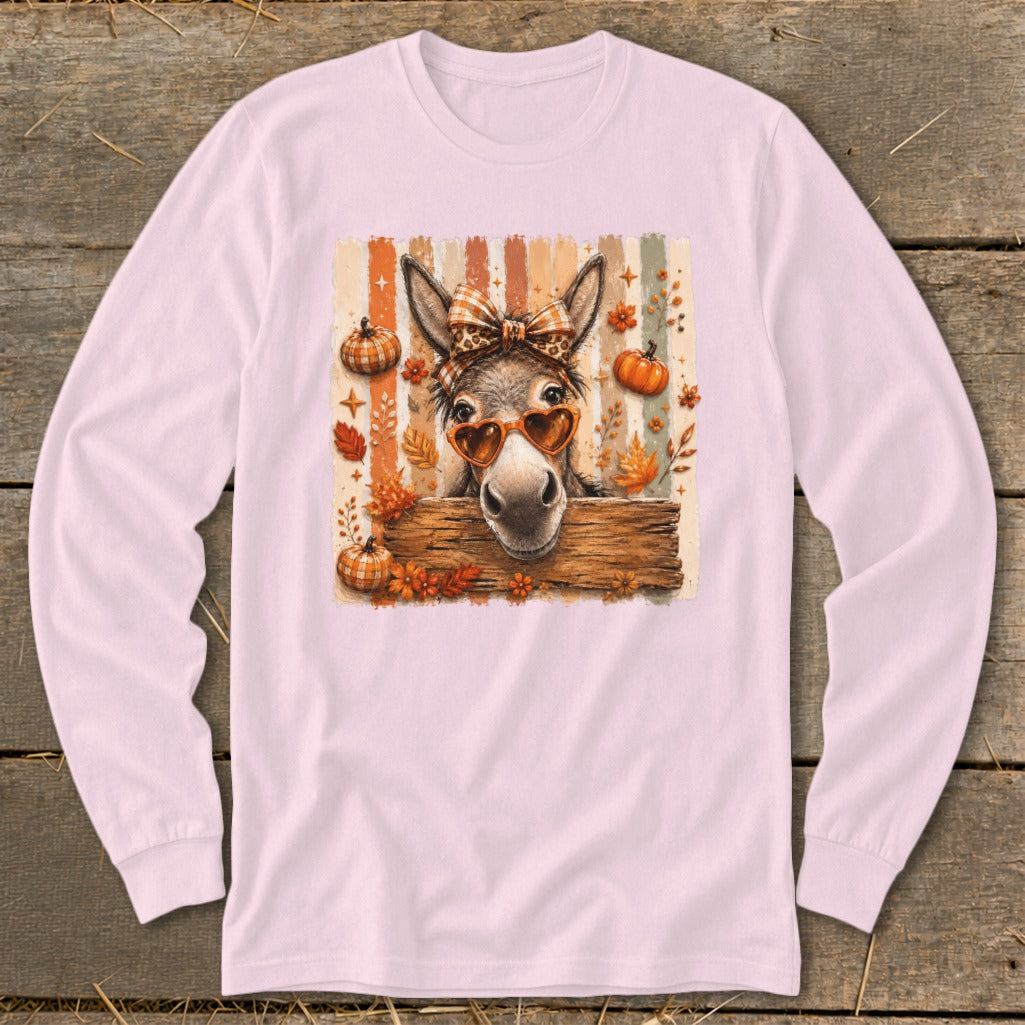 Donkey wearing heart sunglasses and bow, surrounded by autumn leaves and pumpkins.