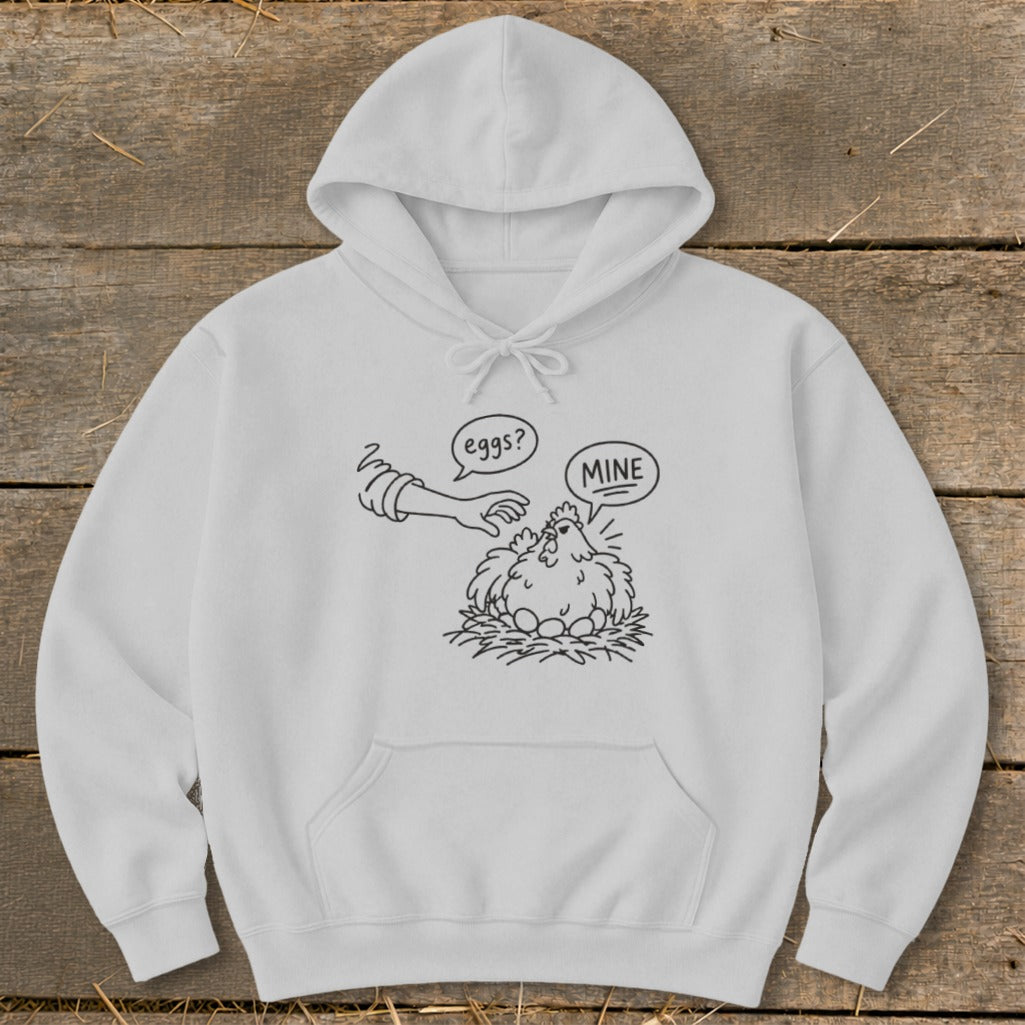 White hoodie with a black line drawing of a chicken guarding eggs with speech bubbles saying "eggs?" and "MINE".