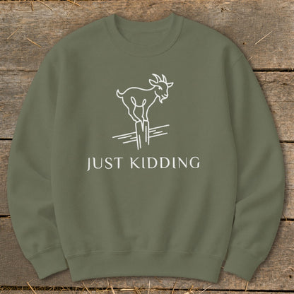 Olive green sweatshirt with white line art of a goat on a post and text "JUST KIDDING".