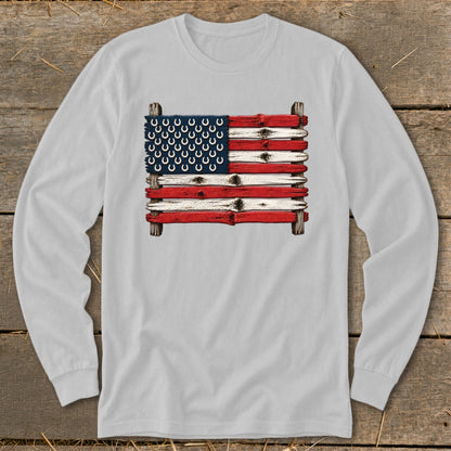 Light gray long-sleeve t-shirt featuring a rustic American flag graphic made of painted wood and horseshoes.