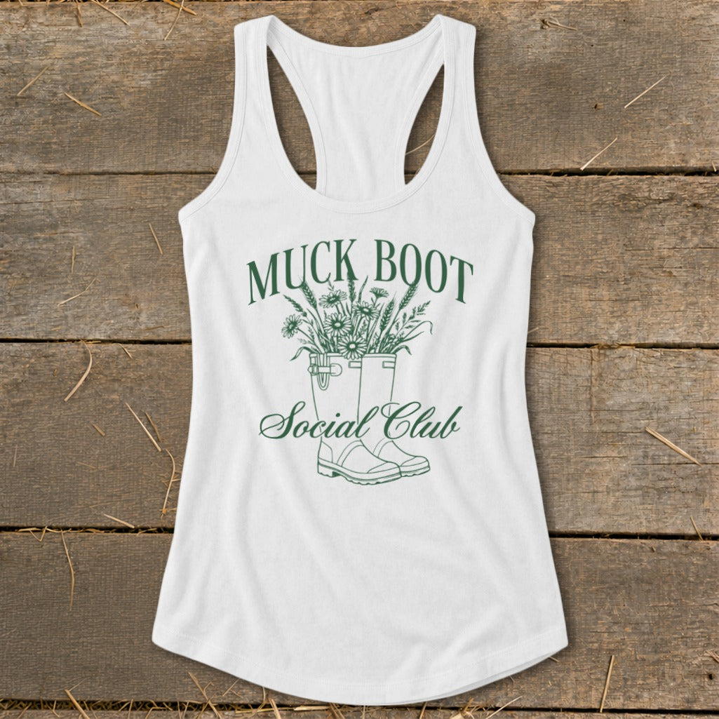 White tank top with green graphic of muck boots filled with flowers and text.