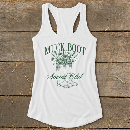 White tank top with green graphic of muck boots filled with flowers and text.